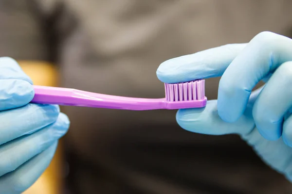 Woman dentist or stomatologist holding and showing purple toothbrush, demonstrates bristle stiffness — Stock Photo, Image