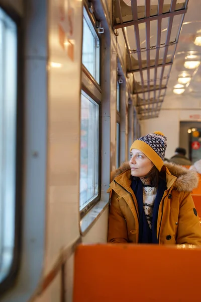 Übermütiges Mädchen, das im Winter mit der S-Bahn unterwegs ist und aus dem Fenster auf die verschneite Landschaft blickt — Stockfoto