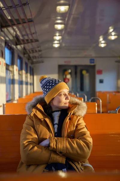 Junge Frau mit Hut fährt im Winter mit der S-Bahn und schaut aus dem Fenster. — Stockfoto