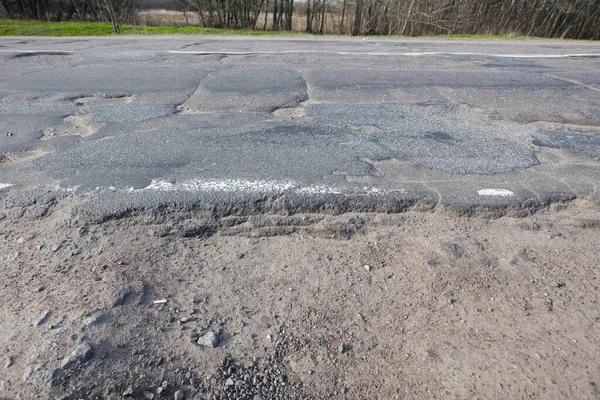 Bad quality road with potholes. Hole in asphalt. Pit, unsafe, hole road. Transportation, destruction of roads, risk of movement by car