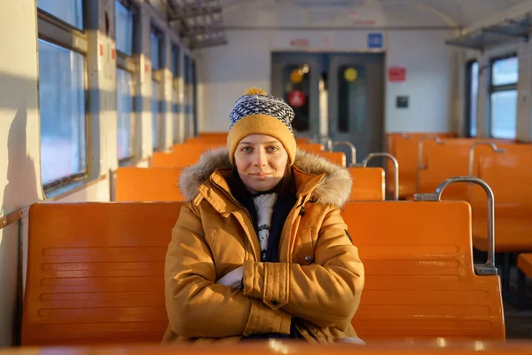Europäerin mit Hut, die im Winter mit der S-Bahn unterwegs ist, gekreuzte Hände, blickt in die Kamera. — Stockfoto