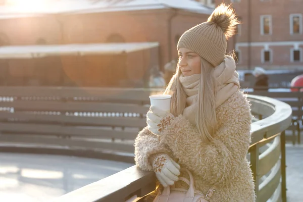 Frauen tragen weiße Fäustlinge, die an kalten, sonnigen Wintertagen eine dampfende weiße Tasse heißen Kaffee oder Tee halten — Stockfoto