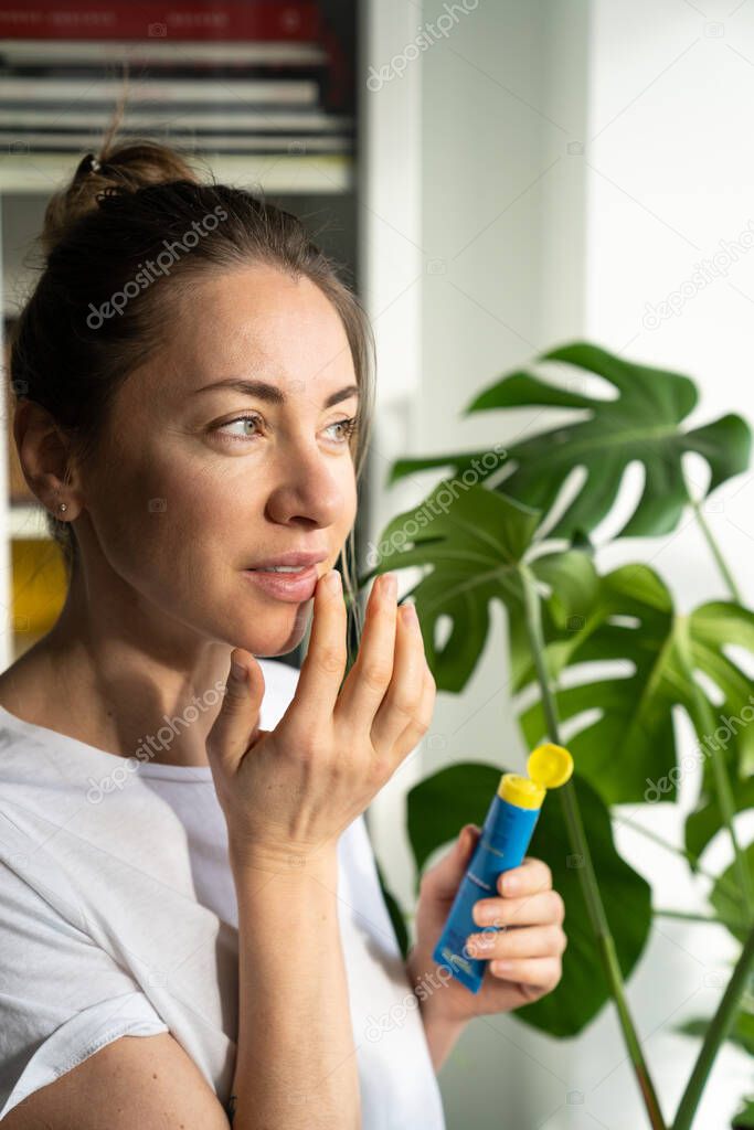 Woman applying moisturizing nourishing balm to her lips to prevent dryness, chapping in cold season