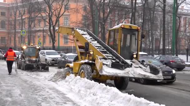Traktor a sněžný pluh odstranit zasněženou silnici po sněžení v Petrohradě, Rusko. Zimní špatné počasí. — Stock video