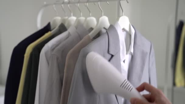 Κοντινό χέρι του ανθρώπου χρησιμοποιώντας επαγγελματικό ατμόπλοιο ένδυμα για τα ρούχα φυσάει ατμού στο σπίτι — Αρχείο Βίντεο