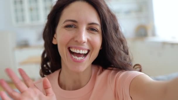 Щаслива жінка відеоблогерів, що розмовляє у відеозв'язку, махає рукою, записує новий контент у відеоблог вдома — стокове відео