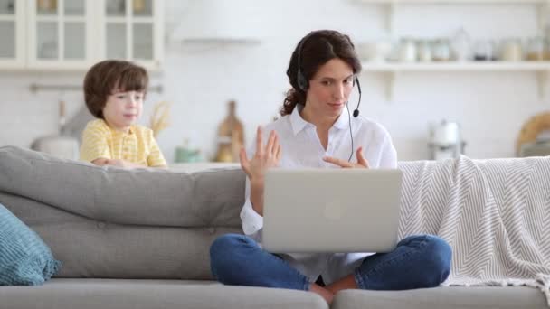 Мама розмовляє на відео дзвінок віддалена робота на ноутбуці з дому з дитиною. Діти роблять шум показує язик — стокове відео