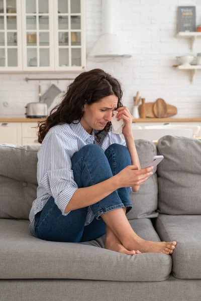Mujer joven llorar leer malas noticias de correo electrónico, mensaje de ruptura ex-novio en el teléfono inteligente sentarse solo en el sofá —  Fotos de Stock