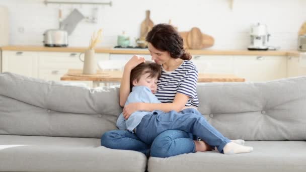 Happy young mom embrace tired after funny games at home son sleeping on her hands — Stock Video