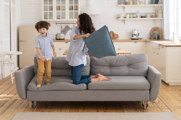 Mom and son having fun in living room fighting with pillows together. Family leisure and recreation time — Stock Photo, Image
