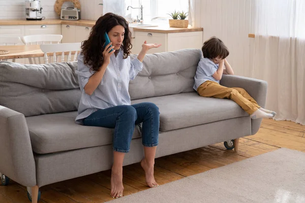 Kleine jongen huilt terwijl mama ruzie maakt met vader tijdens een telefoongesprek. Depressieve zoon moe van familie gevechten — Stockfoto