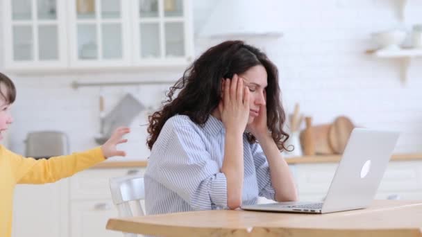 Noisy kid distracts mom from work pulls sleeve and hair, asking attention from annoyed busy mother — Stock Video