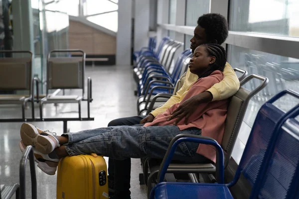 Afrikanisches Paar schläft auf Stühlen im Wartezimmer des Flughafens, müde warten auf verspäteten oder Transitflug — Stockfoto