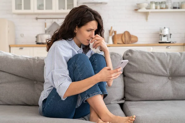 Jonge vrouw huilen lees slecht nieuws e-mail, ex-vriendje uit elkaar bericht op smartphone zitten eenzaam op de bank — Stockfoto