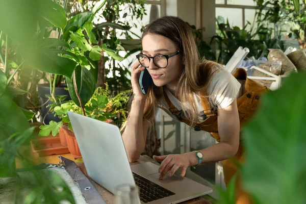 Wolny strzelec kobieta praca z domu, kwiaciarnia przedsiębiorca w zdalnym biurze używać laptopa w krytym ogrodzie — Zdjęcie stockowe