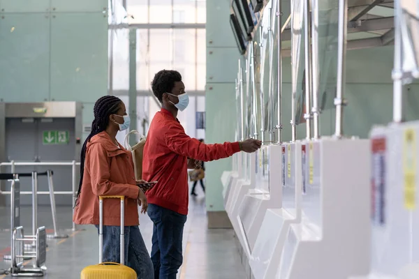 Paar mit Maske am Check-in-Schalter im Flughafen vor dem Flug während der Coronavirus-Epidemie — Stockfoto