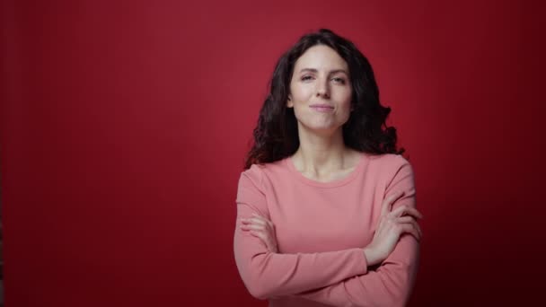 Portret van zelfverzekerde vrouwelijke kruising armen en glimlachende glimlach geïsoleerd op rode studio muur achtergrond — Stockvideo