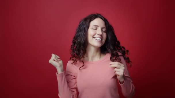 Wanita yang sangat bahagia melakukan tarian pemenang merayakan keberhasilan berita baik atas latar belakang studio merah — Stok Video