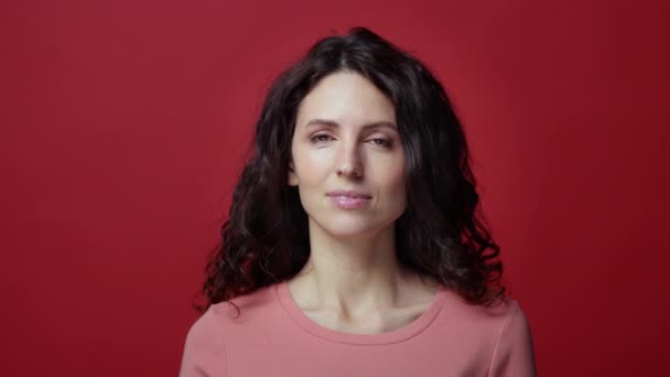 Portret van vrolijke glimlachende vrolijke mooie vrouw met krullend haar geïsoleerd over rode achtergrond — Stockvideo