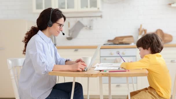 Mamma donna d'affari, lavoro freelance remoto sul computer portatile, figlio disegno sedersi insieme a tavola in cucina — Video Stock