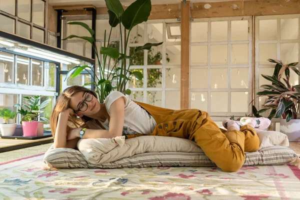 Chica artista, diseñador de interiores, jardinero descanso en el suelo en estudio vintage con viejas ventanas y plantas —  Fotos de Stock