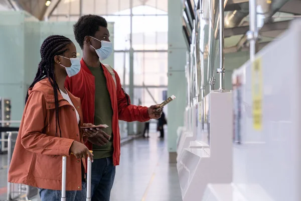 Paar mit Maske am Check-in-Schalter im Flughafen vor dem Flug während der Coronavirus-Epidemie — Stockfoto