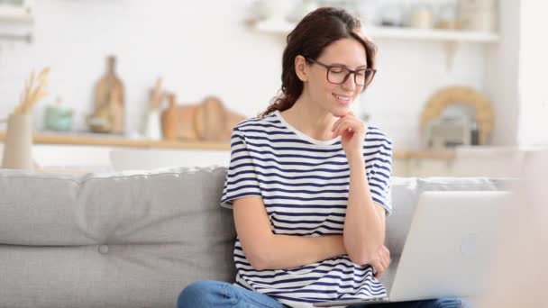 Millennial dáma s notebookem na pohovce pohled s nadějí na monitoru číst e-mail rozhovor loterie výsledky — Stock video