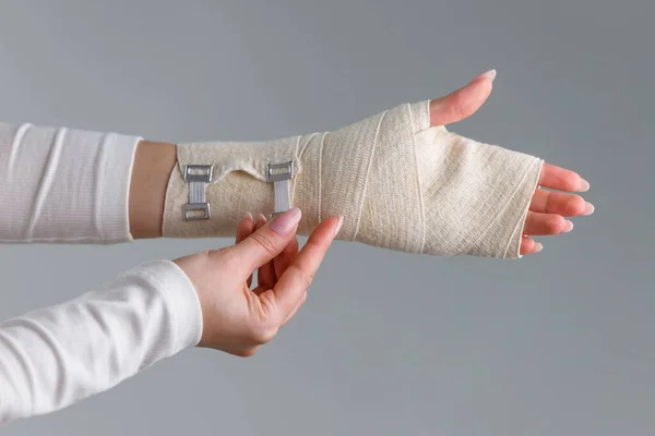 Close up of woman wrapping her painful wrist with flexible elastic supportive orthopedic bandage after unsuccessful sports or injury. Carpal tunnel syndrome, arthritis, arm sprain concept.