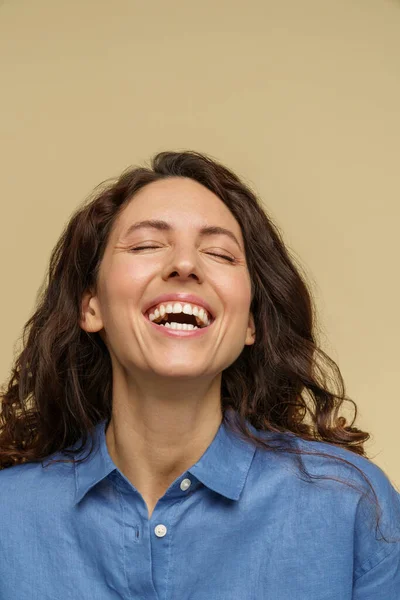 Nadšený nadšený kudrnatý dívka izolované na béžové pozadí smích s otevřenými ústy a zavřené oči — Stock fotografie