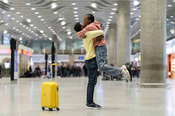 Liebespaar glücklich Treffen nach langer Zeit. Afrikaner und Frau umarmen sich aufgeregt im Flughafen-Terminal — Stockfoto