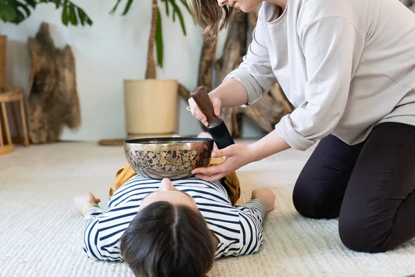 Jonge vrouw heeft tibet massage, zingende kom therapie met traditionele Tibetaanse bronzen bekkens thuis — Stockfoto