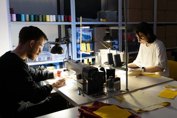 Zwei Schneiderinnen nähen im Atelier an Nähmaschinen. Team von Bekleidungsdesignern und Unternehmern arbeitet zusammen — Stockfoto