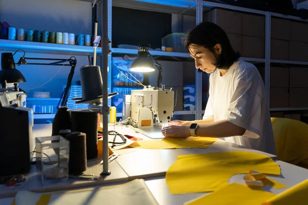 专业工作室里，年轻设计工作室的女老板在缝纫机上缝衣 — 图库照片