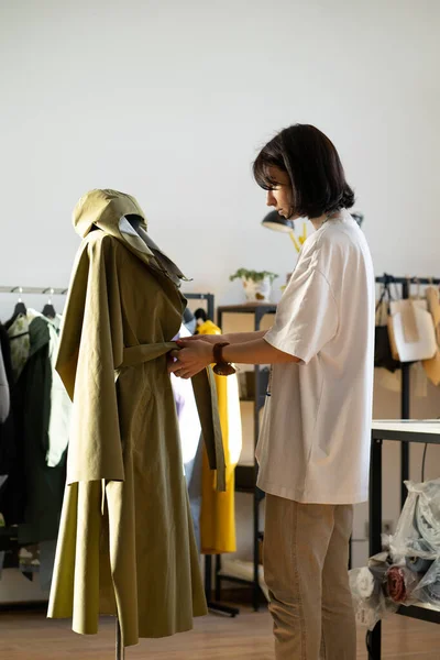 Designer ajuster manteau sur mannequin en studio. Travailleuse d'atelier travaillant à la collection en atelier — Photo