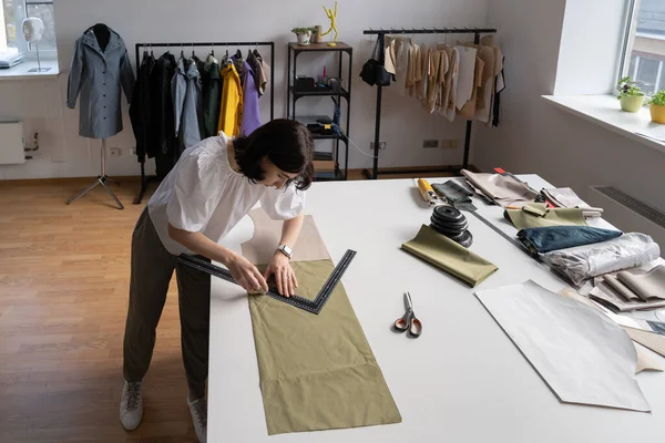 Young tailor work with cloth. Designer, sewer, atelier owner measure fabric draw pattern for clothes — Stock Photo, Image