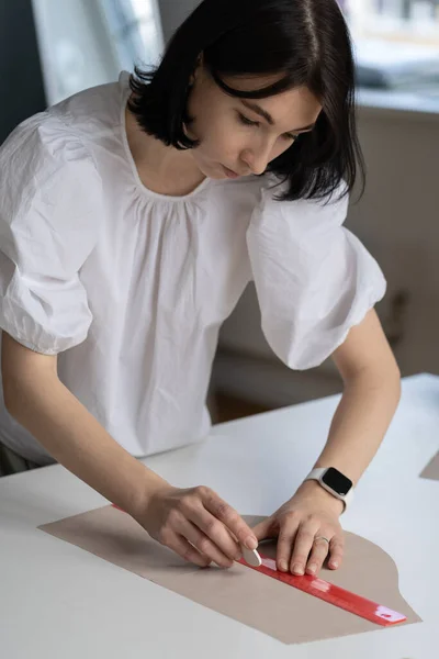 Hembra sastre utilizar la regla para dibujar patrón de tela para cortar el material. Diseñador o costurera en taller — Foto de Stock