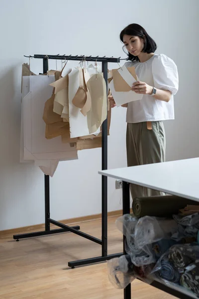 Fashion designer hold paper patterns in studio. Young woman seamstress or atelier owner in workshop — Stock Photo, Image