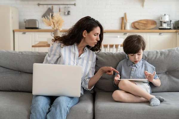 Mère travailleur indépendant aider son fils avec le doigt de la tablette à l'écran numérique comme travail à distance de la maison — Photo