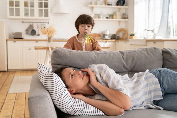 La madre joven y cansada despierta con un niño pequeño hace ruidos. exhausto mami acostado en sofá tratar de dormir o descansar —  Fotos de Stock