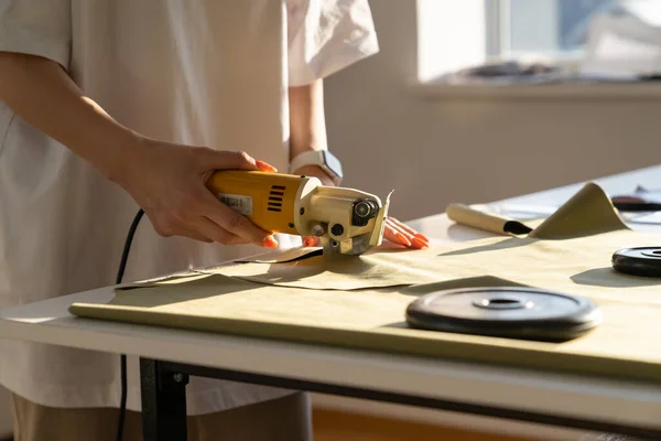 Designer gebruik maken van elektrische cutter voor het snijden van stof werk in de studio. Sluiting van een op maat gesneden doek om te naaien — Stockfoto