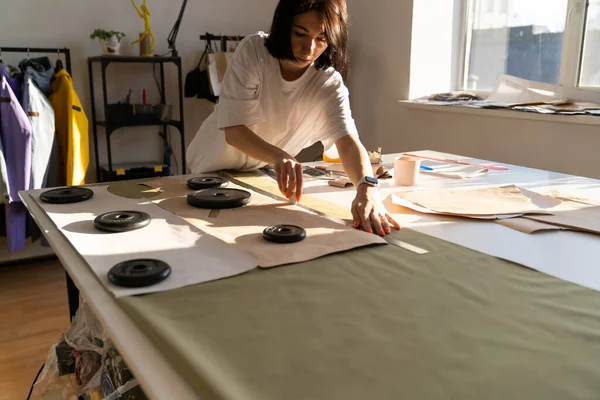 Costurera dibujar patrones de papel en textil con tiza y regla. Trabajo de diseñador de ropa en estudio — Foto de Stock