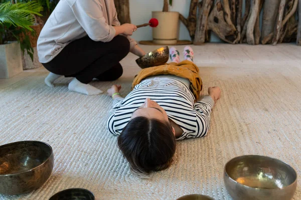 Dos mujeres hacen masajes tibetanos en casa, practican la terapia de sonido tibetana juntas para meditar — Foto de Stock