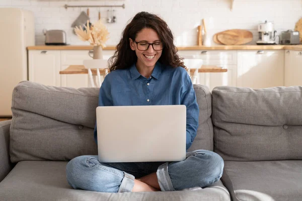 Overjoyed ragazza casuale ridere sul divano con computer portatile in ginocchio leggere messaggi divertenti o guardare video online — Foto Stock