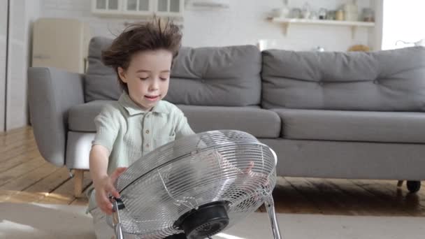 可爱的男孩夏季酷热，享受着从复古风扇空调机吹来的新鲜凉爽的微风 — 图库视频影像