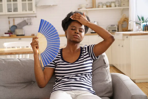 Fekete nő szenved hőguta lakás nélkül légkondicionáló integető ventilátor feküdt a kanapén otthon — Stock Fotó