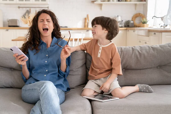 Overwhelmed mom helpless scream stressed with disobedient preschool son distract from surfing web