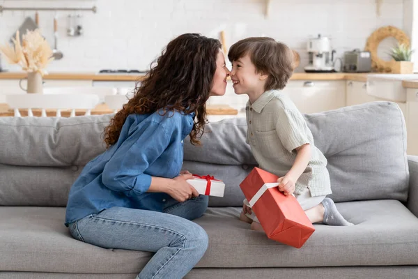 誕生日、バレンタインデー、クリスマス:お母さんと息子の絆は、手にギフトボックスとソファの上に座っています — ストック写真