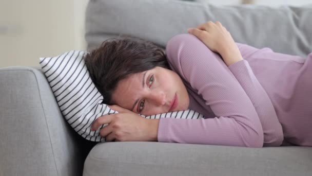 Спокойная девушка спит на диване. Уставшая кавказка отдыхает на удобном диване после работы дома — стоковое видео