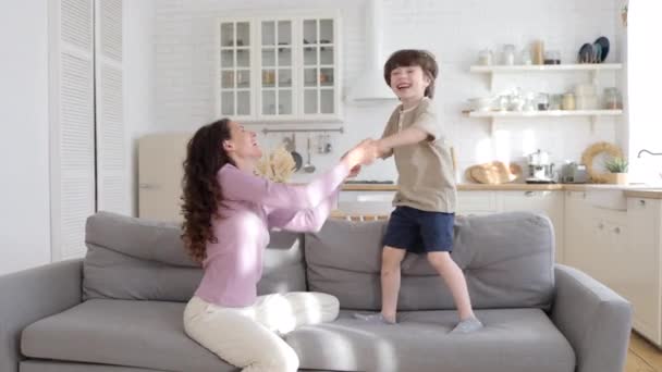 Verheugd moeder en zoon van vijf dansen in de woonkamer grappig verhuizen naar modern lied in het weekend thuis — Stockvideo