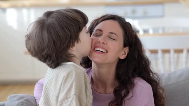 Small boy kiss joyful mother. Overjoyed happy mom and cute preschool son cuddling together at home — Stockvideo